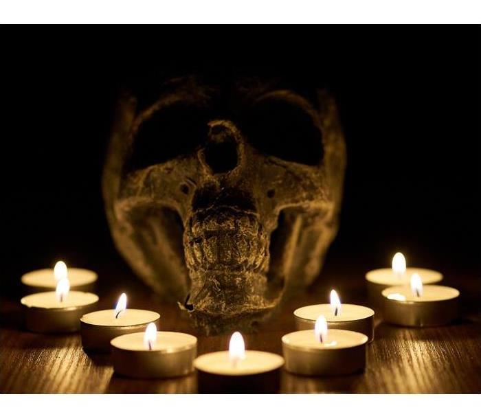 Lit tea candles around a decorative skull